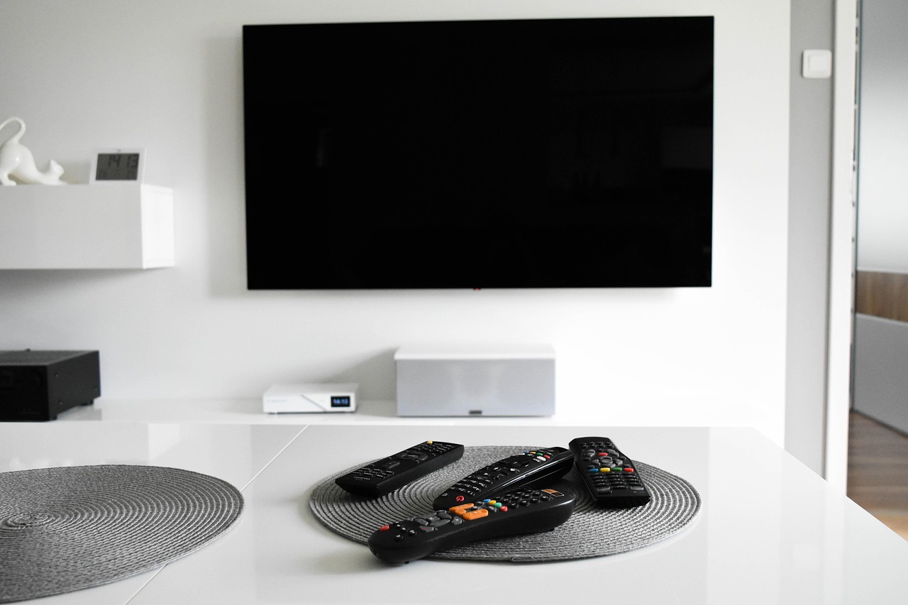 壁掛けテレビと並べて置いた複数のリモコン